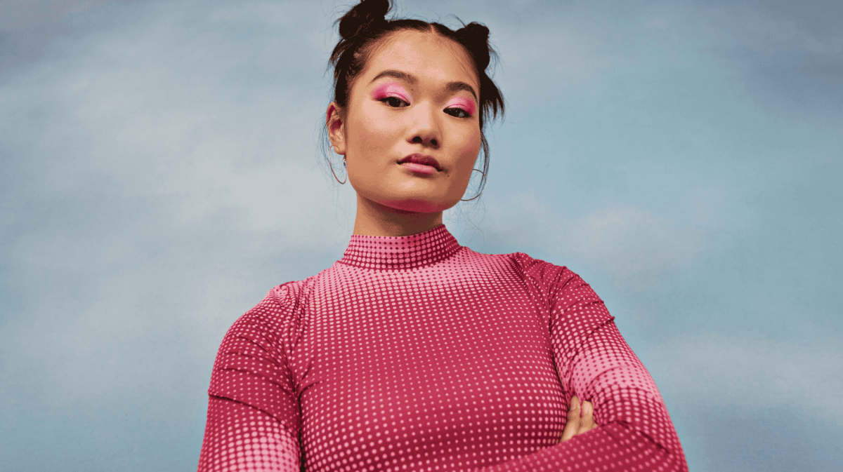 Frau mit pinkem Pullover schaut selbstbewusst in die Kamera