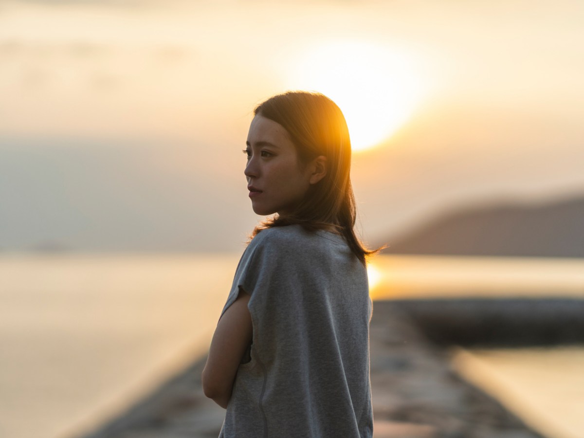 Frau auf einem Steg im Sonnenuntergang