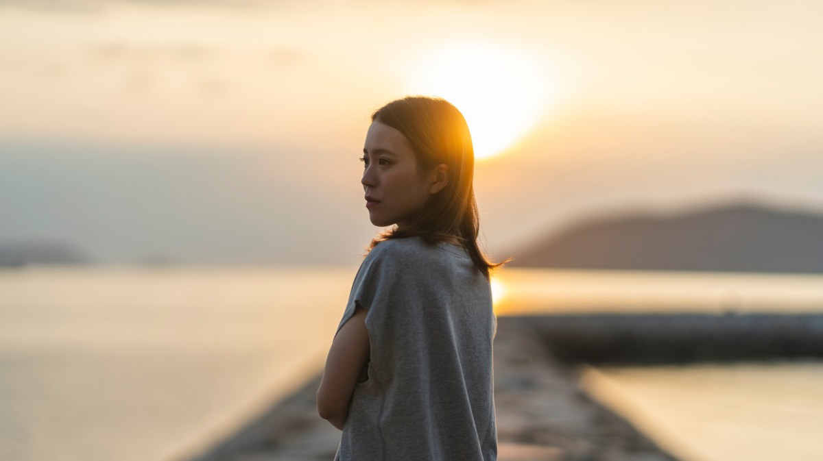 Frau auf einem Steg im Sonnenuntergang