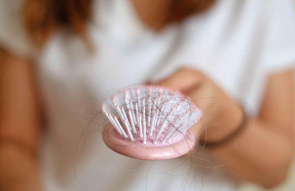 Eine Frau h&auml;lt eine Haarb&uuml;rste in der Hand