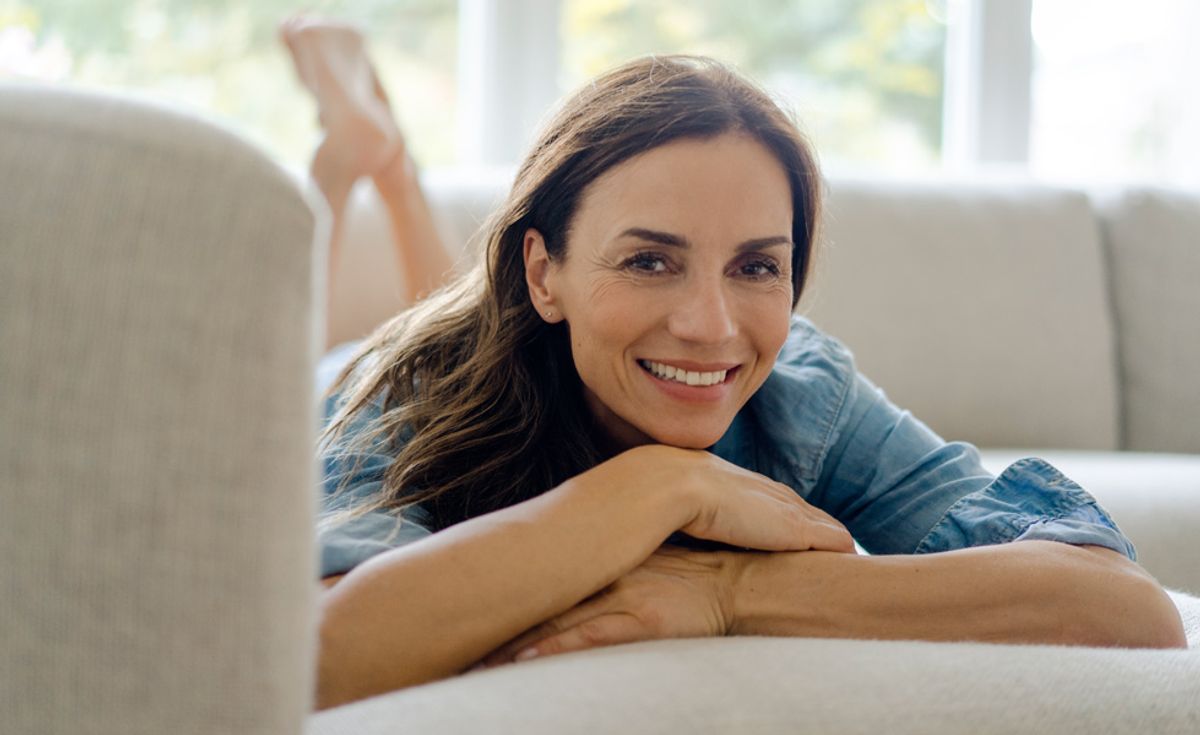 Frau mittleren Alters liegt auf dem Bauch im Bett.