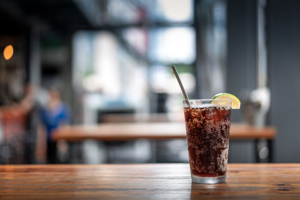 Ein Glas Cola mit Zitrone steht in einem Restaurant auf dem Tisch.