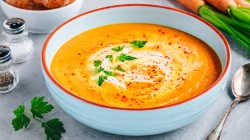Karotten-Suppe in einer wei&szlig;en Sch&uuml;ssel mit rotem Rand