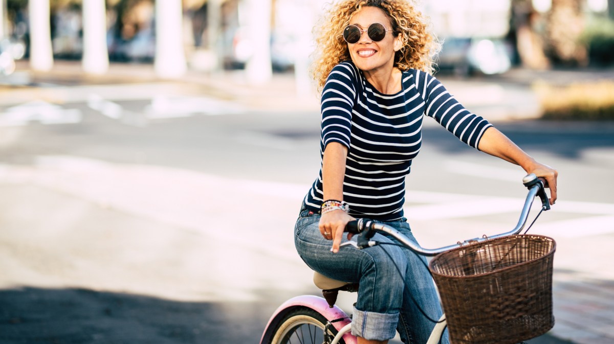 Frau mit Sonnenbrille auf dem Fahrrad in der Stadt