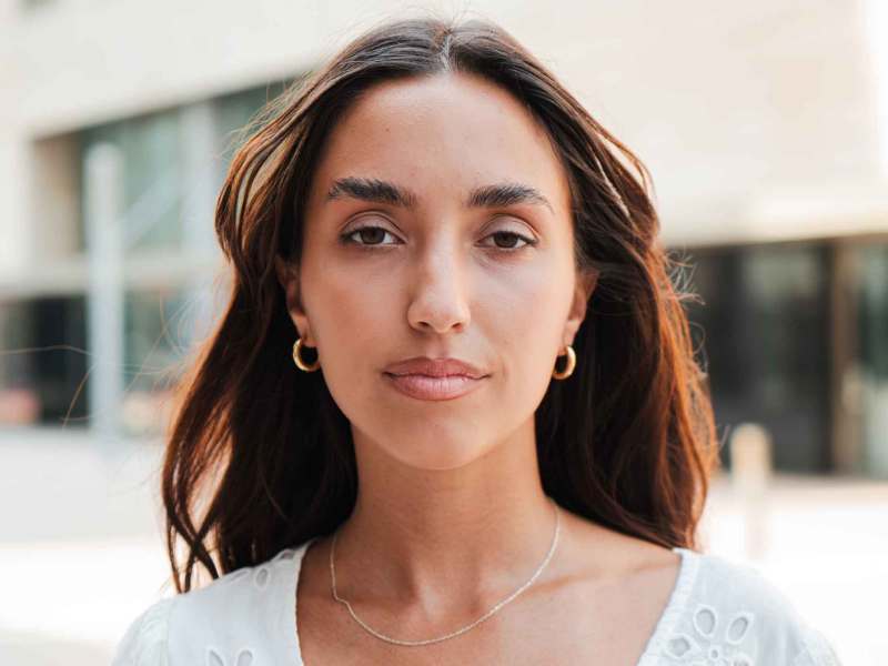 Braunhaarige Frau guckt neutral.