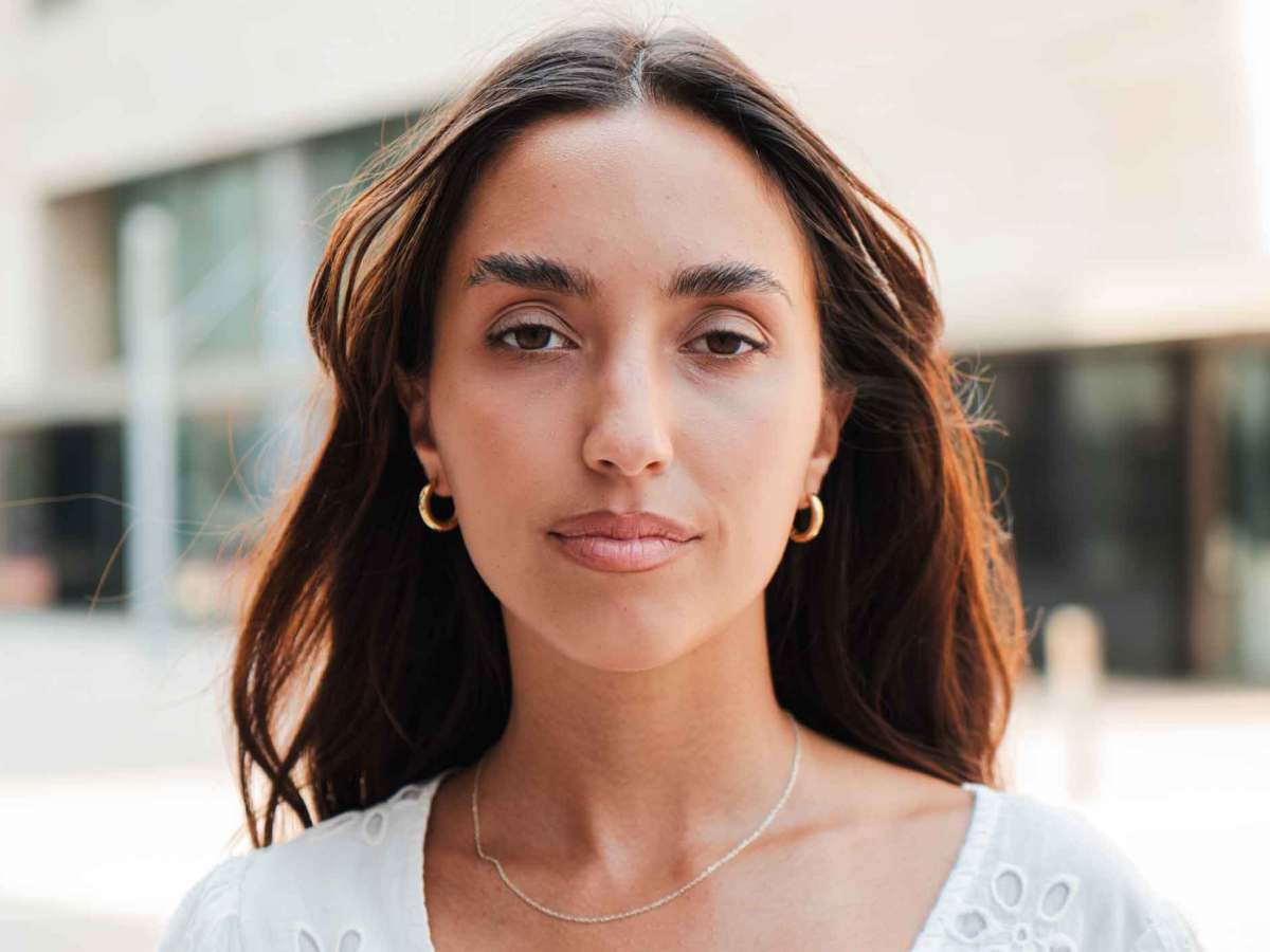 Braunhaarige Frau guckt neutral.