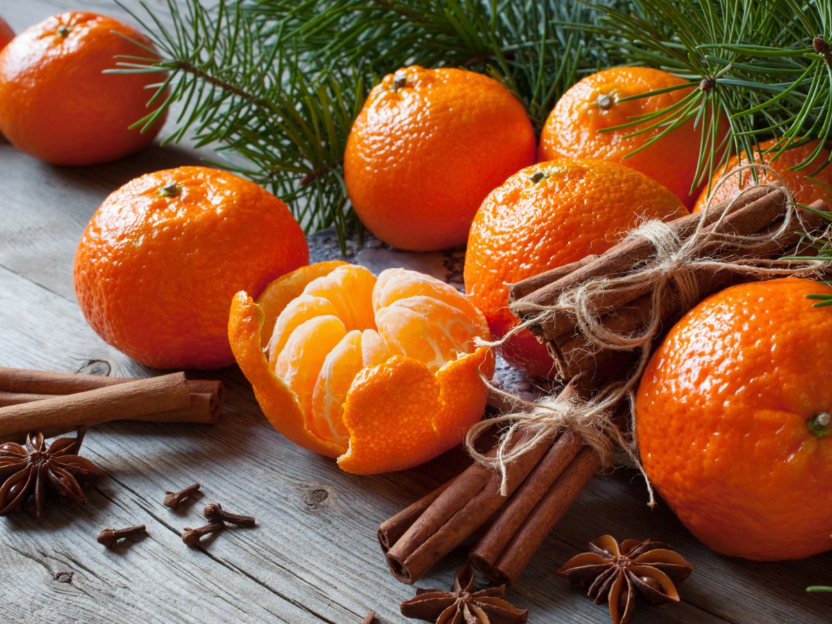 Mandarinen neben Tannengrün und Zimtstangen.