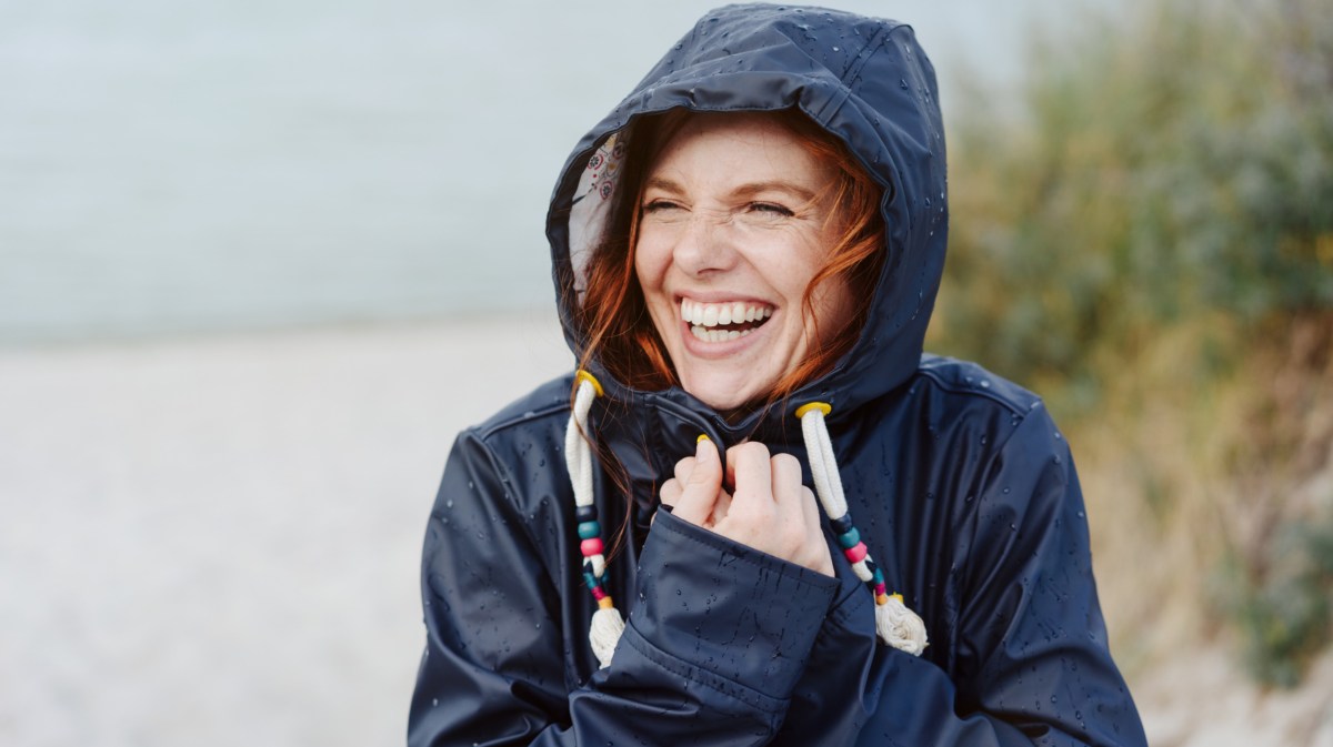 Frau mit Regenjacke lächelt.