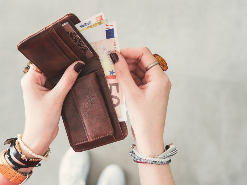 Frau holt Geld aus dem Portemonnaie