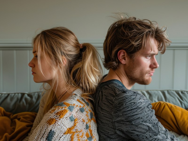 Mann und Frau, R&uuml;cken an R&uuml;cken, die traurig nach vorne blicken.