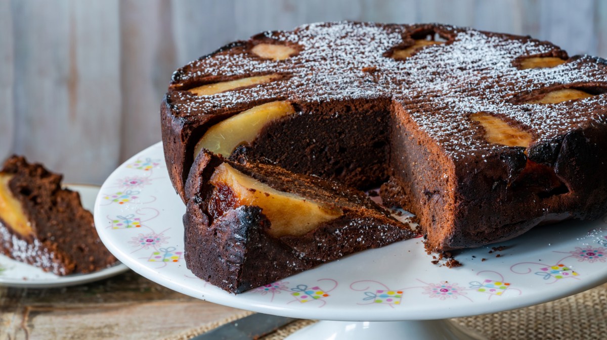 Schoko-Birnen-Kuchen auf weißer Servierplatte.