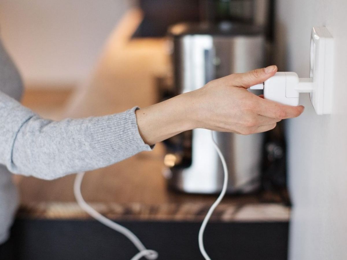 Frau steckt einen Wasserkocher ein.