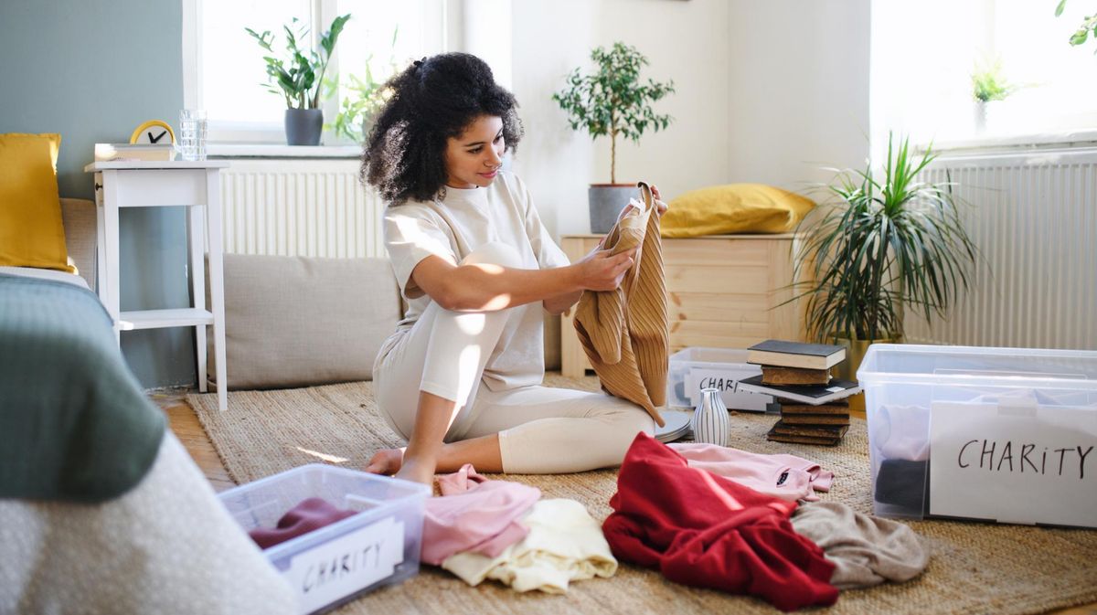 Frau sitzt auf dem Boden sortiert ihre Klamotten aus