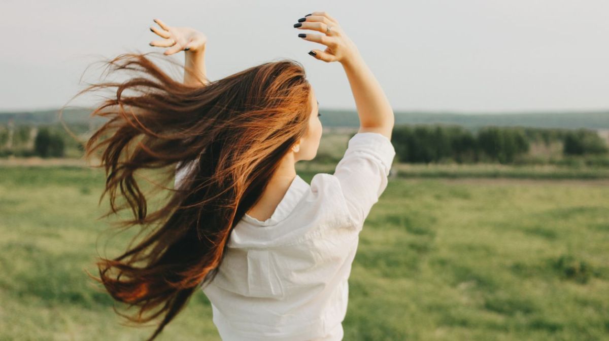 Frau auf einem Feld, mit Wind im Haar 