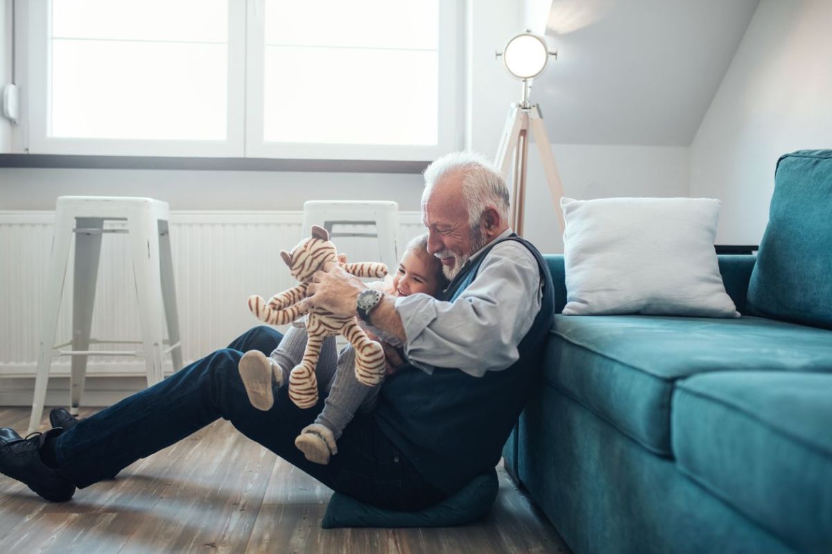 Großvater und Enkeltochter spielen im Wohnzimmer zusammen.