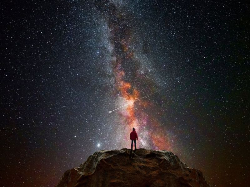 Frau schaut in den Sternenhimmel auf einem Berg 