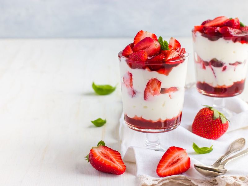 Schichtdessert mit Käsekuchen und Erdbeeren im Glas.