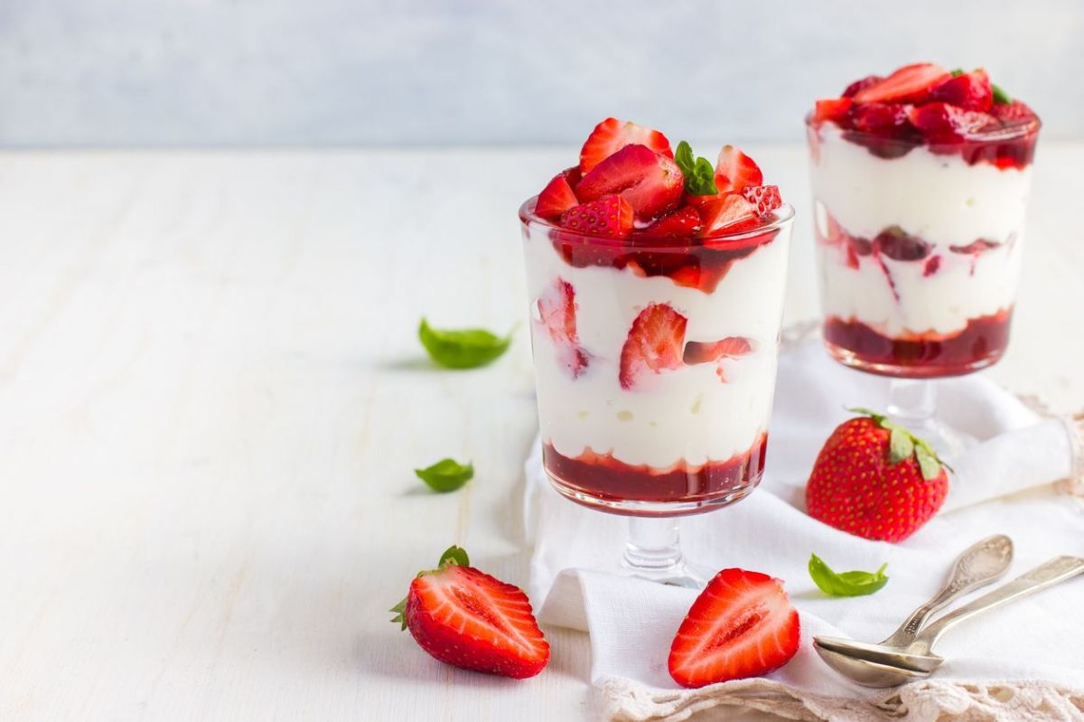 Schichtdessert mit Käsekuchen und Erdbeeren im Glas.