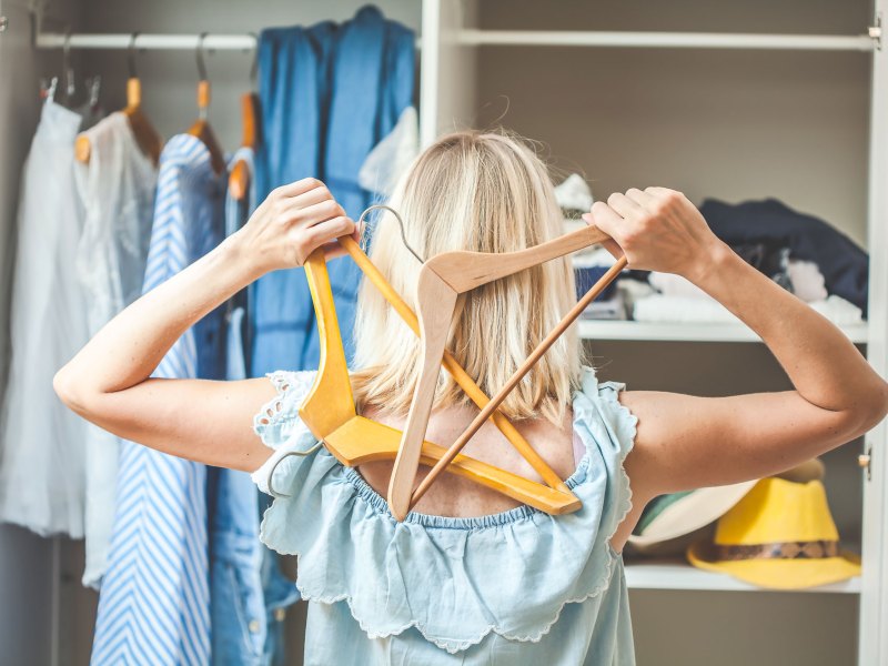 Frau, die vor ihrem vollen Kleiderschrank steht