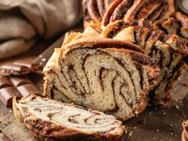 Babka mit Schokoladenfüllung auf rustikalem Holzbrett.