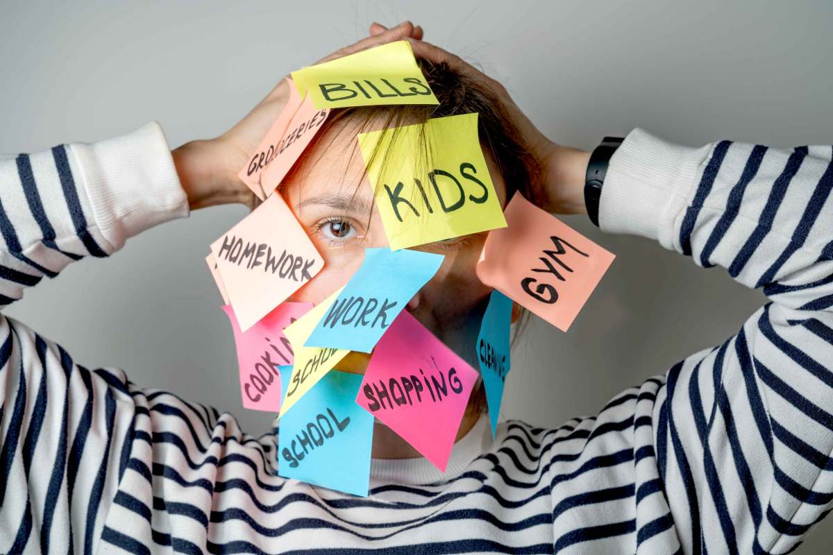 Frau hat Post-its in verschiedenen Farben mit alltäglichen Aufgaben an ihrem Kopf kleben.