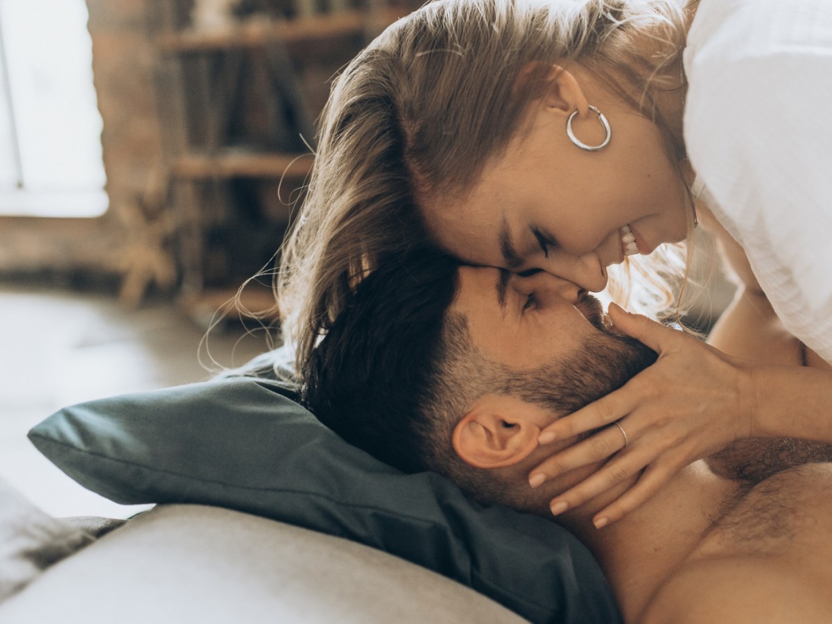 Frau und Mann auf der Couch, die sich anl&auml;cheln und verliebt anschauen