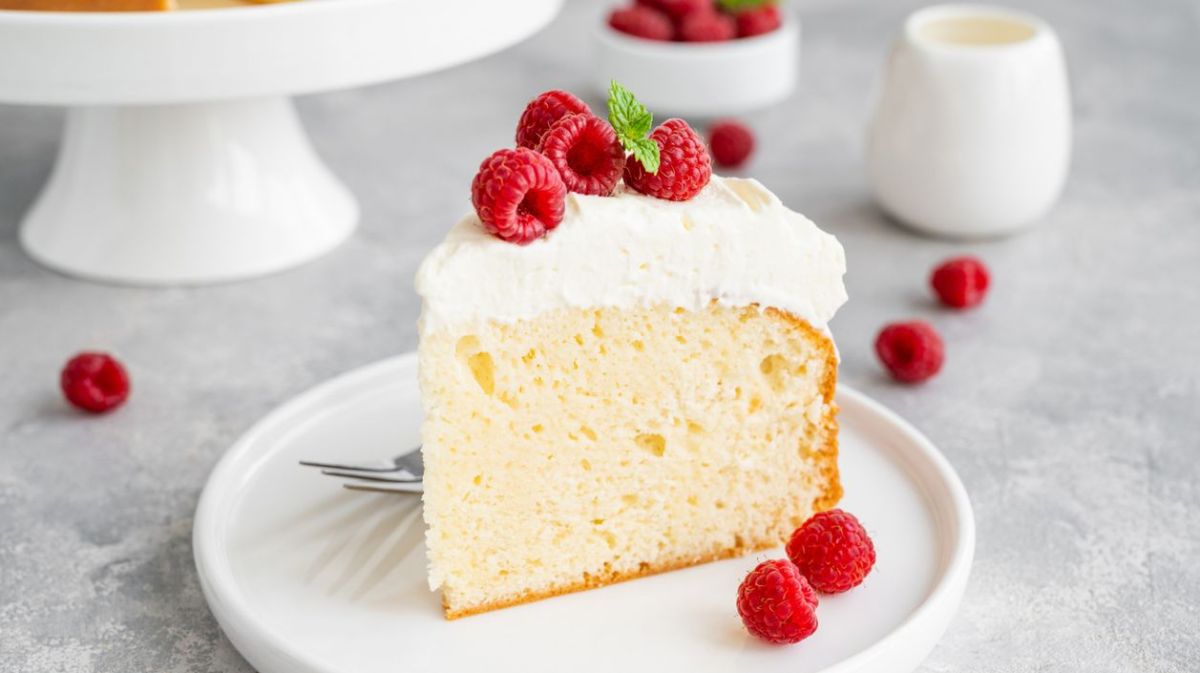 Heller Milchkuchen auf einem weißen Teller mit frischen Himbeeren.