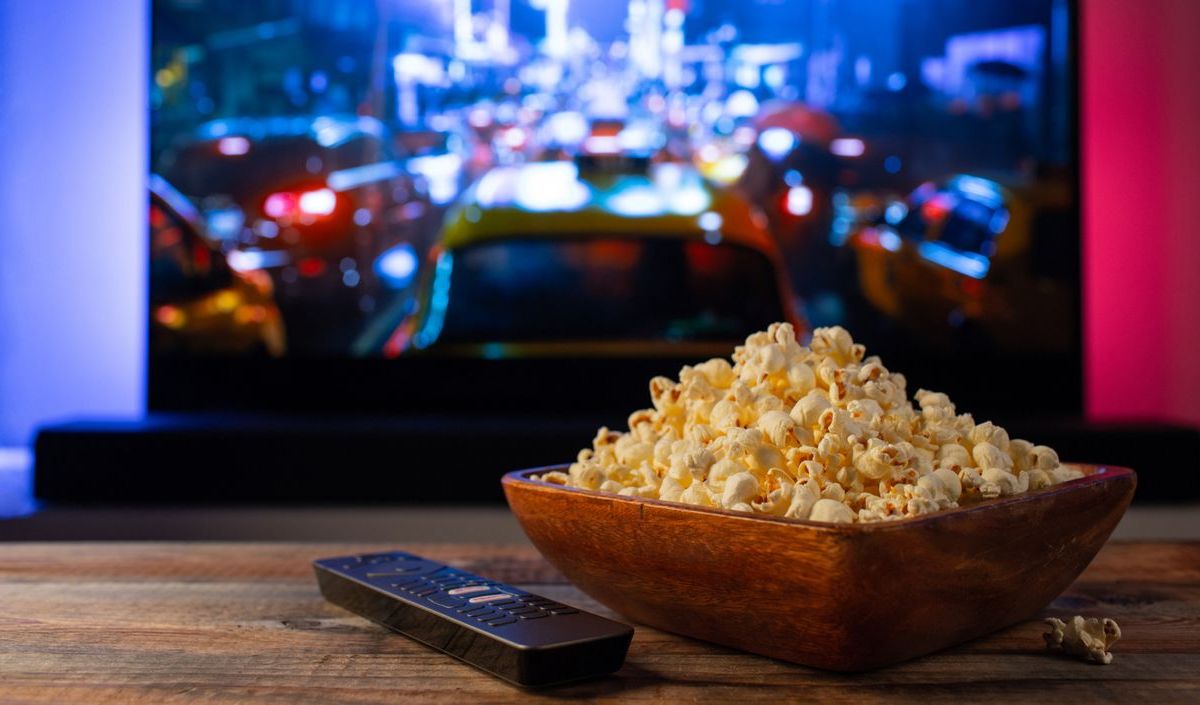 Fernseher mit Fernbedingung und Popcorn auf dem Tisch