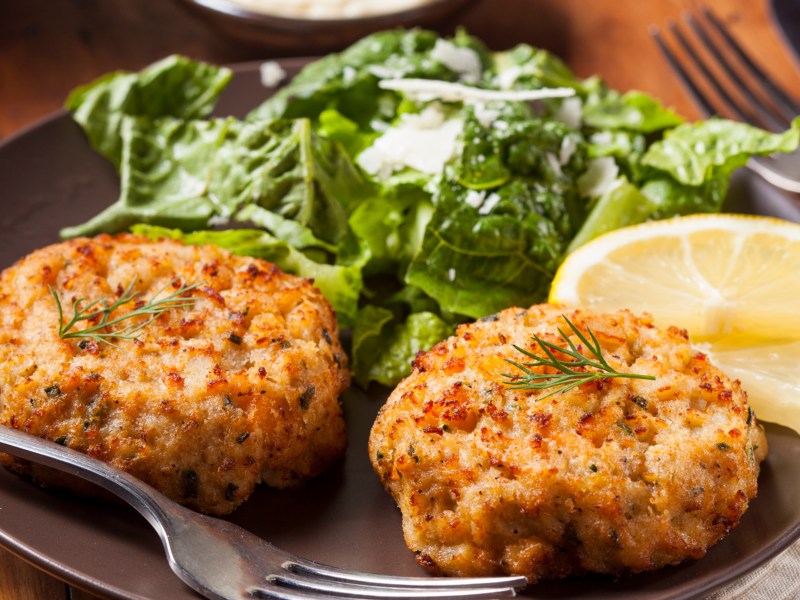 Crab Cakes mit Salat und einer Zitronenscheibe.