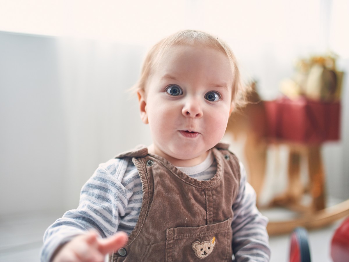 Porträt eines niedlichen 1 Jahr alten kleinen Jungen auf dem Boden sitzend.