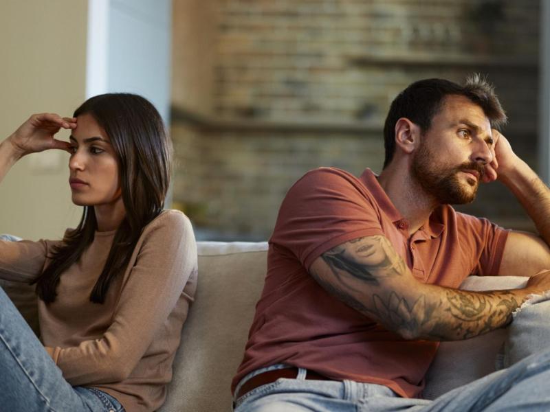 Frau und Mann sitzen Rücken an Rücken