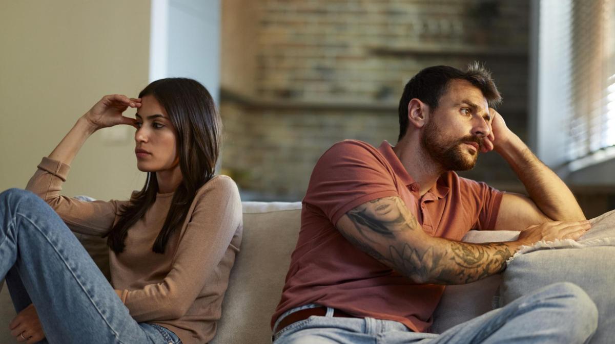 Frau und Mann sitzen Rücken an Rücken