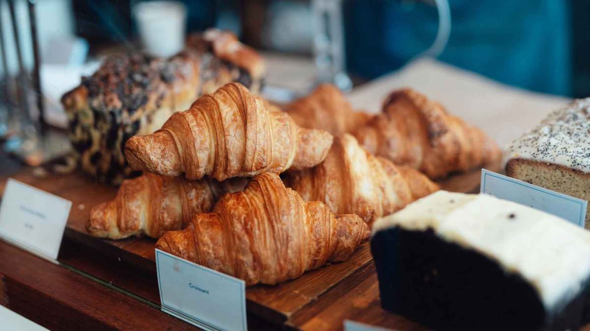 Backwaren einer Bäckerei. Im Vordergrund liegen Croissants.