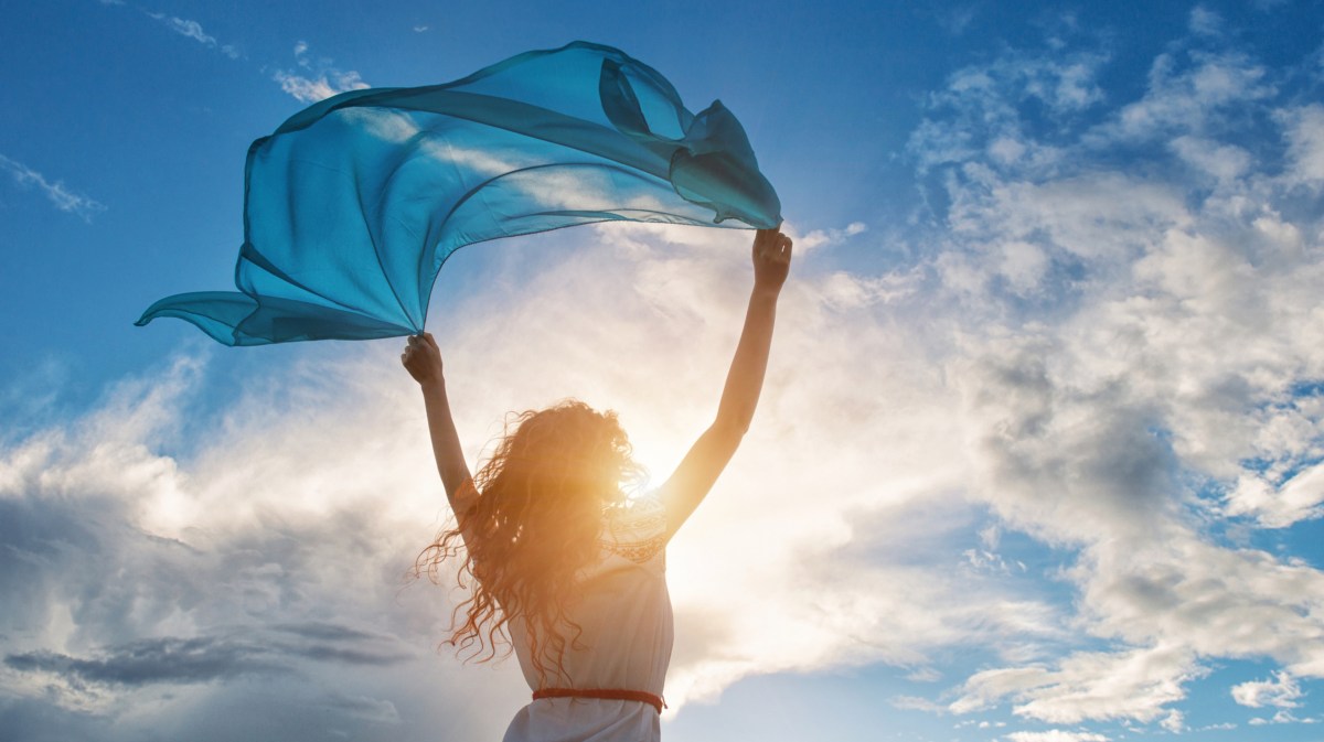 Frau hält Tuch in die Luft, blauer Himmel