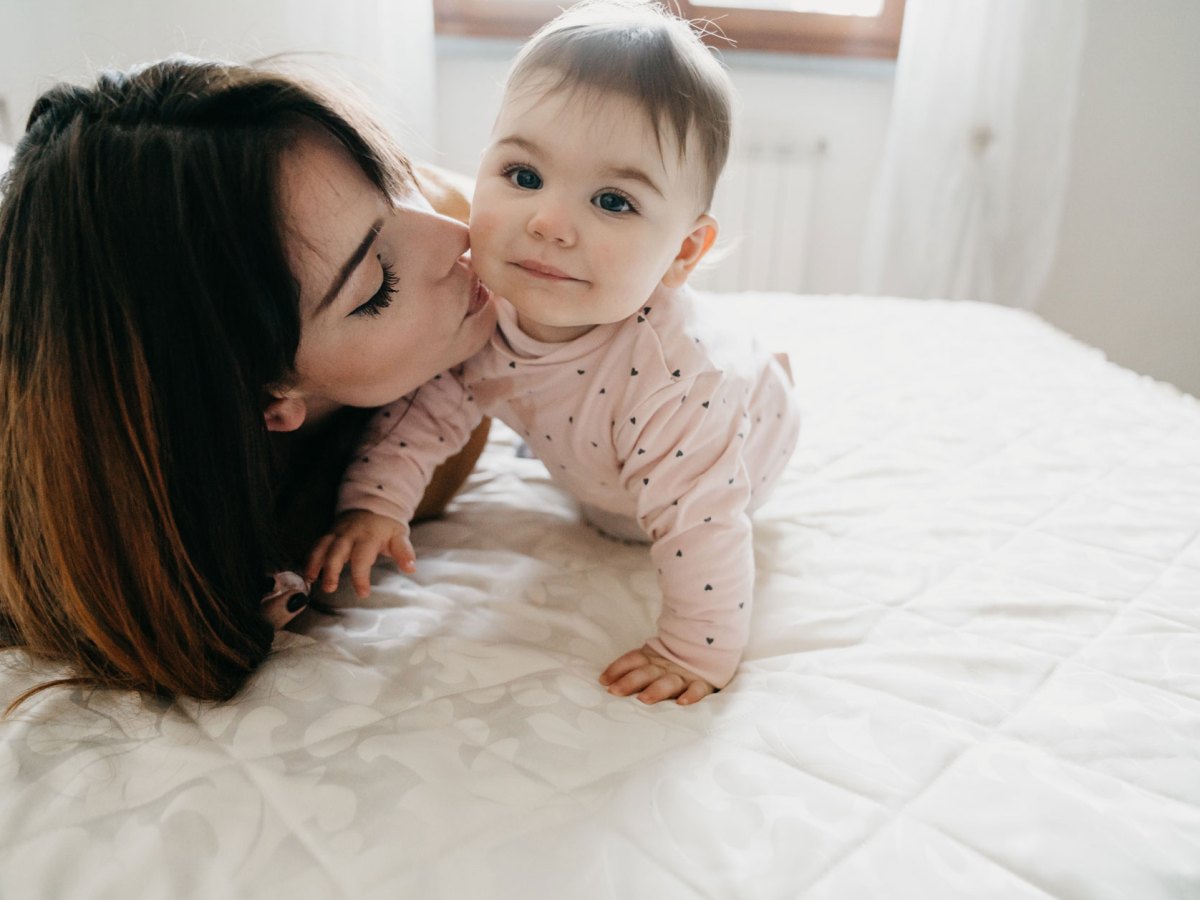 Frau küsst ihr Baby auf die Wange