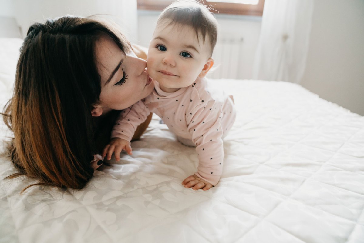 Frau küsst ihr Baby auf die Wange