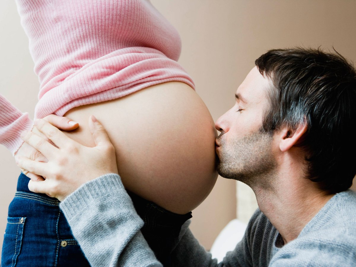 Mann k&uuml;sst Babybauch seiner Frau