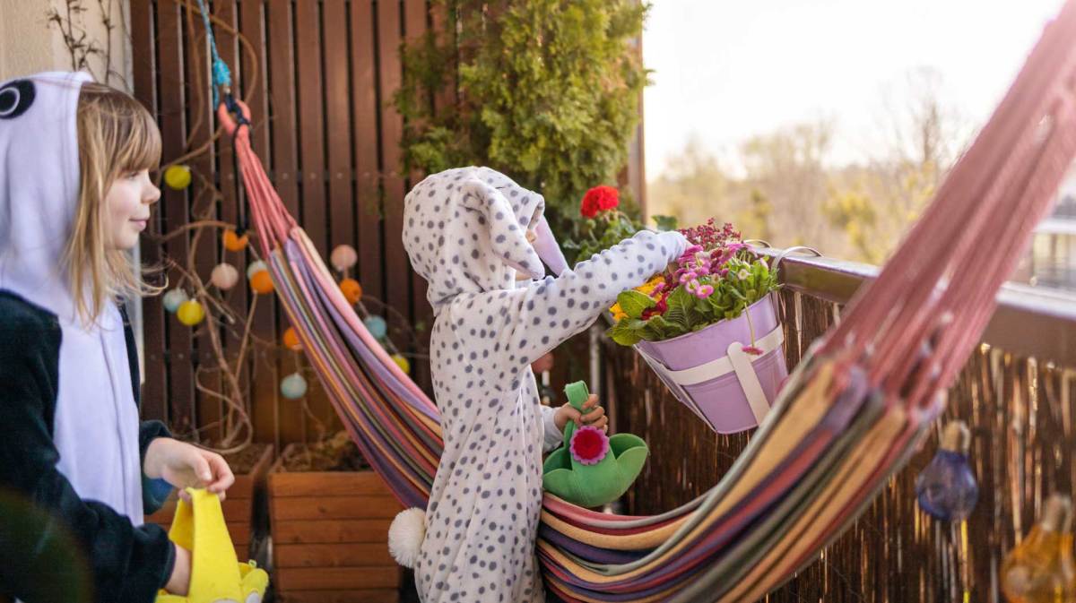 Zwei Kinder, noch in Pyjamas, suchen auf dem Balkon nach Ostereiern.