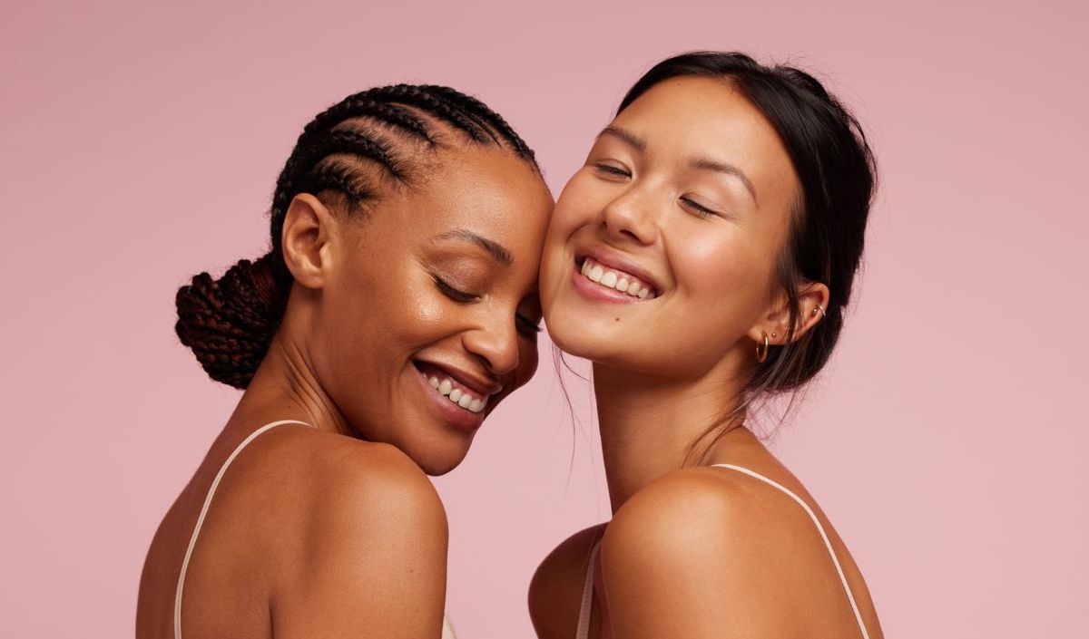 Zwei Frauen am Lachen vor rosafarbenen Hintergrund