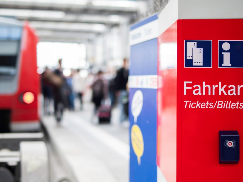 Fahrkartenautomat mit Bahn im Hintergrund