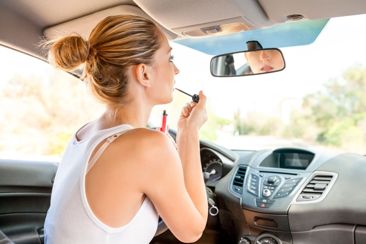 Frau schminkt sich im Auto