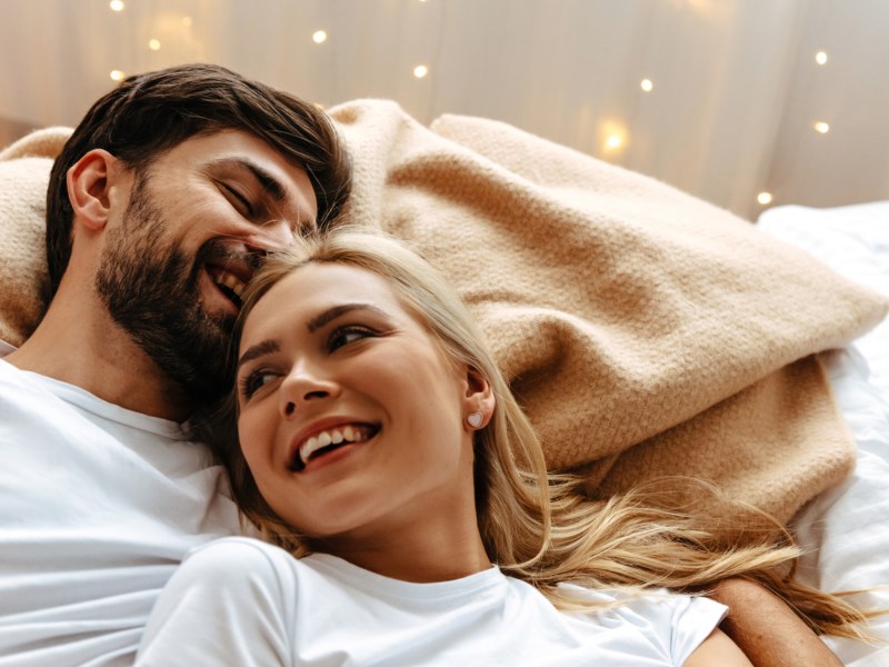 Frau und Mann kuscheln lachend im Bett