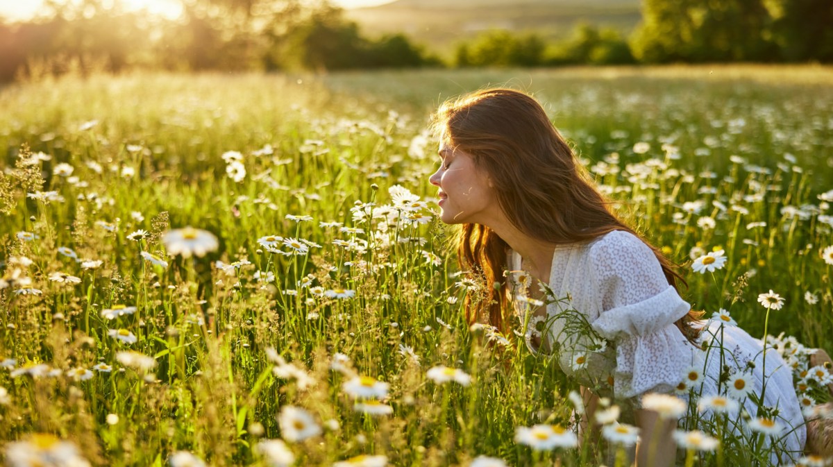 Frau auf Wiese, die an Blumen riecht