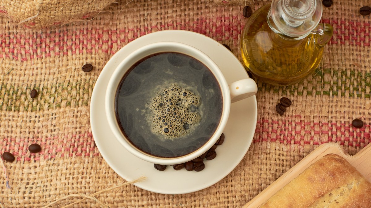 Kaffeetasse und Karaffe mit Olivenöl stehen auf einem Tisch