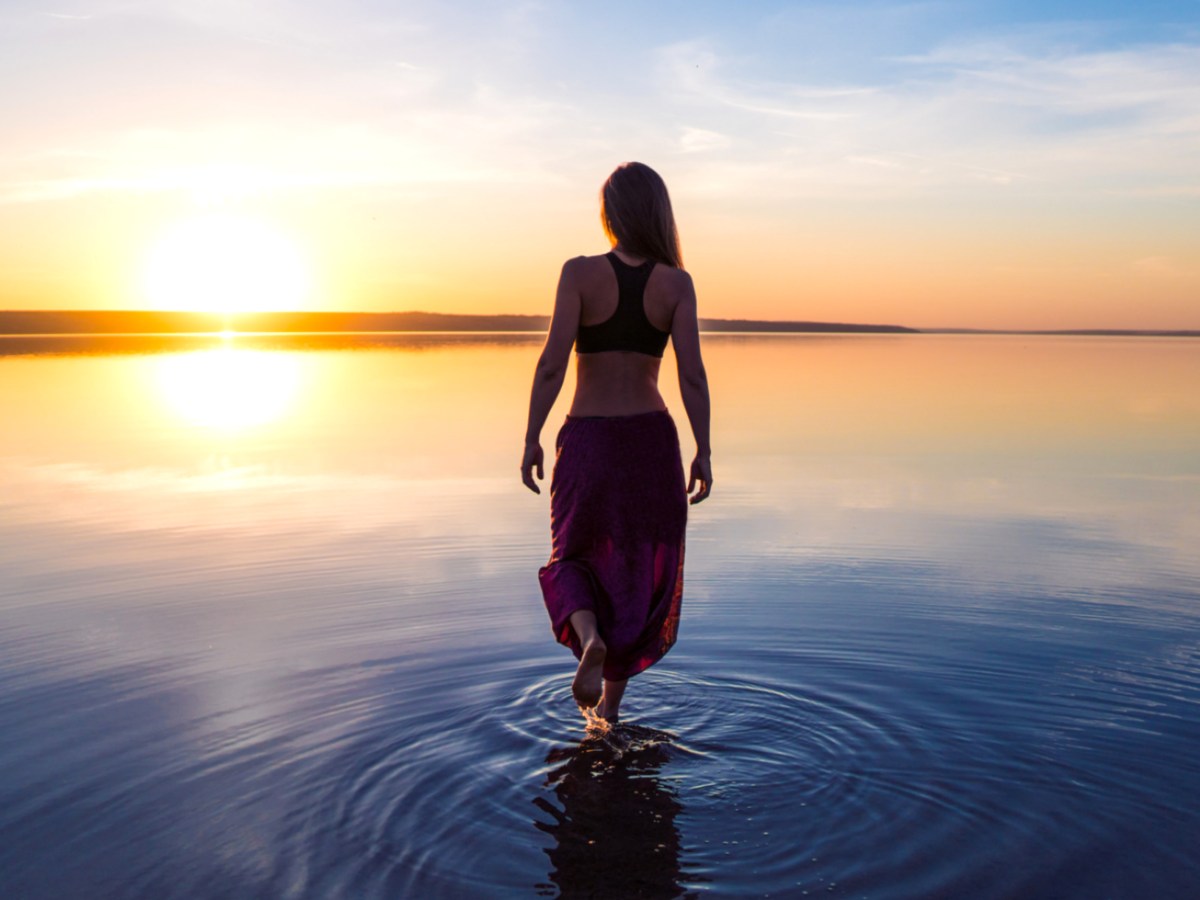 Frau steht mit langem Kleid im Wasser