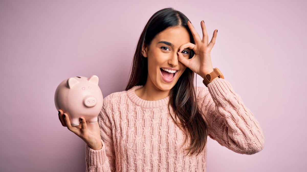 Frau vor lila Hintergrund mit Sparschwein in der Hand