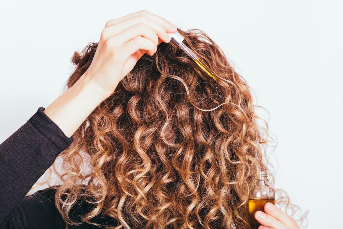 Frau mit Locken wendet Haaröl an