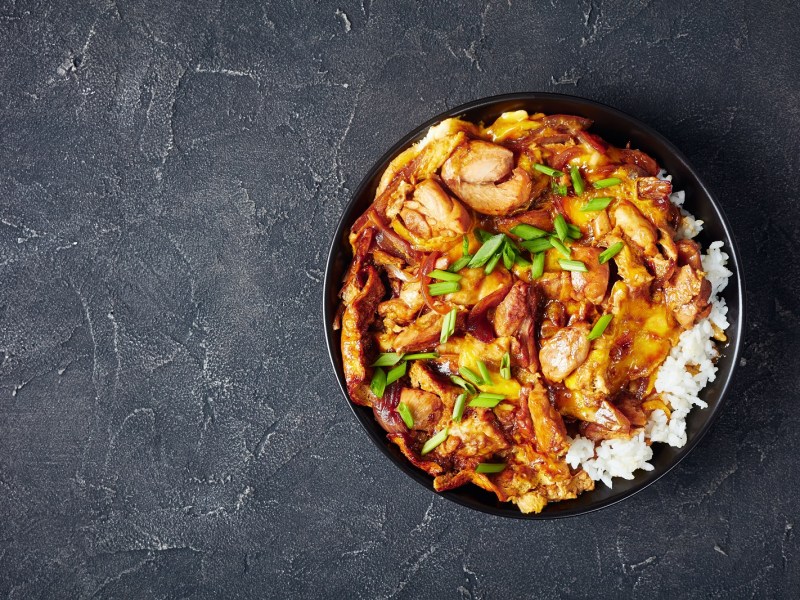 Eine Schüssel Oyakodon auf einem grauen Hintergrund.