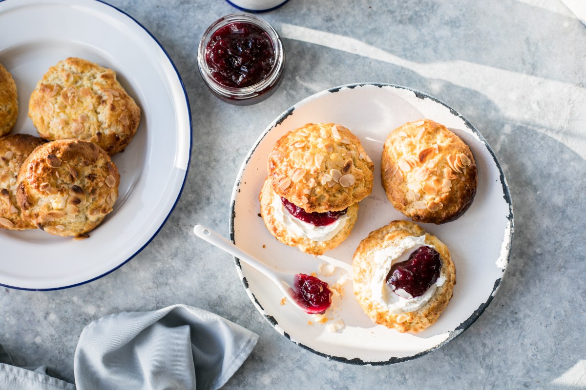 Scones mit Clotted Cream und Marmelade auf Teller.