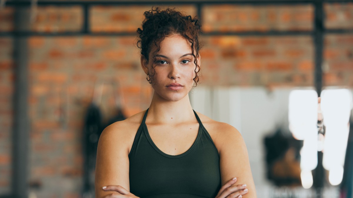 Frau im Fitnessstudio mit eingeschränkten Armen und ernstem Blick